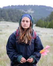 Woman in field with background of mountains holding pin flags.